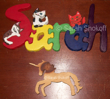 wooden cut outs of the name "Sarah"in a rainbow of colour with cats on it, and a unicorn